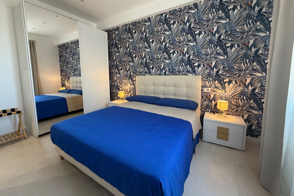 Double bedroom with a mirrored wardrobe and blue leaf wallpaper
