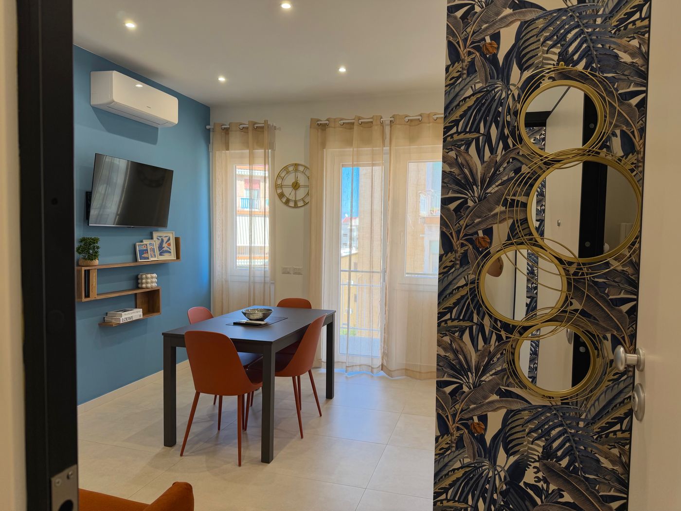 Living room seen from the entrance, with a light blue wall, table and terracotta chairs