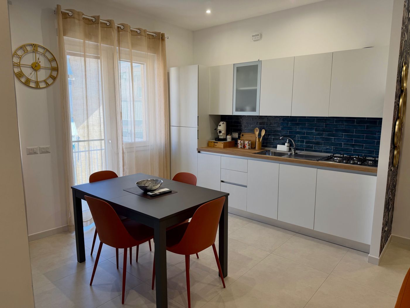 White kitchen with blue tiles and a dining table by the window