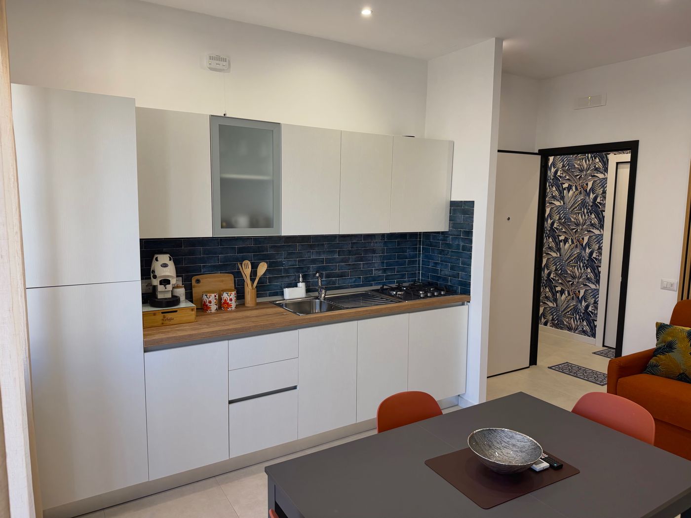 Full kitchen with fridge, oven, hob and blue tiles