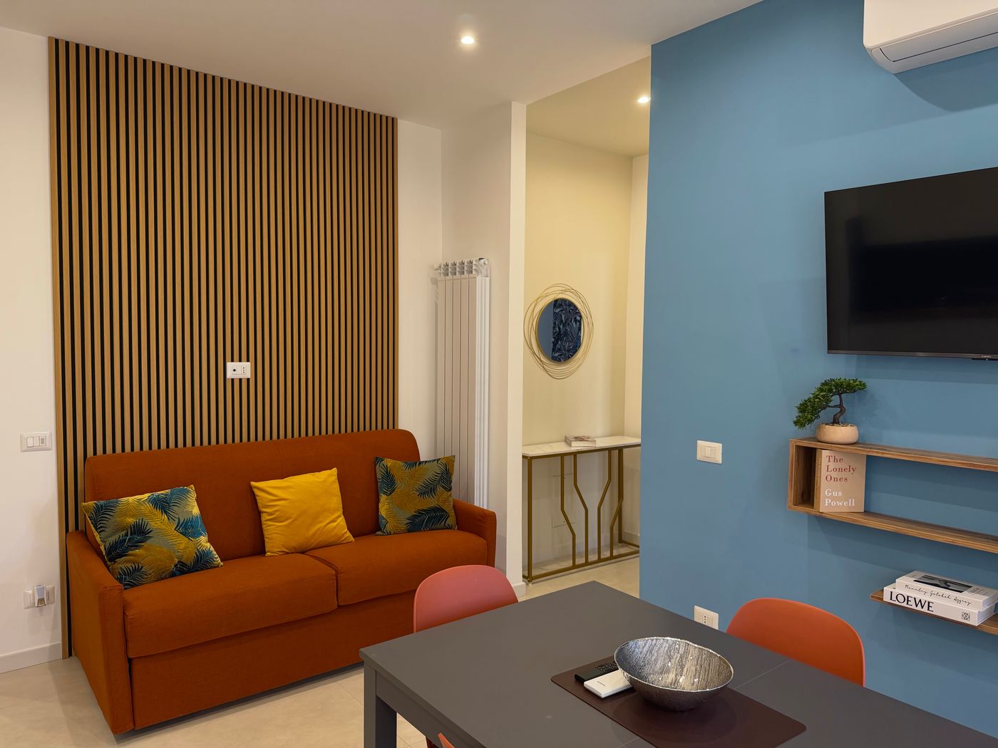 Orange sofa bed, dining table and light blue wall with the TV