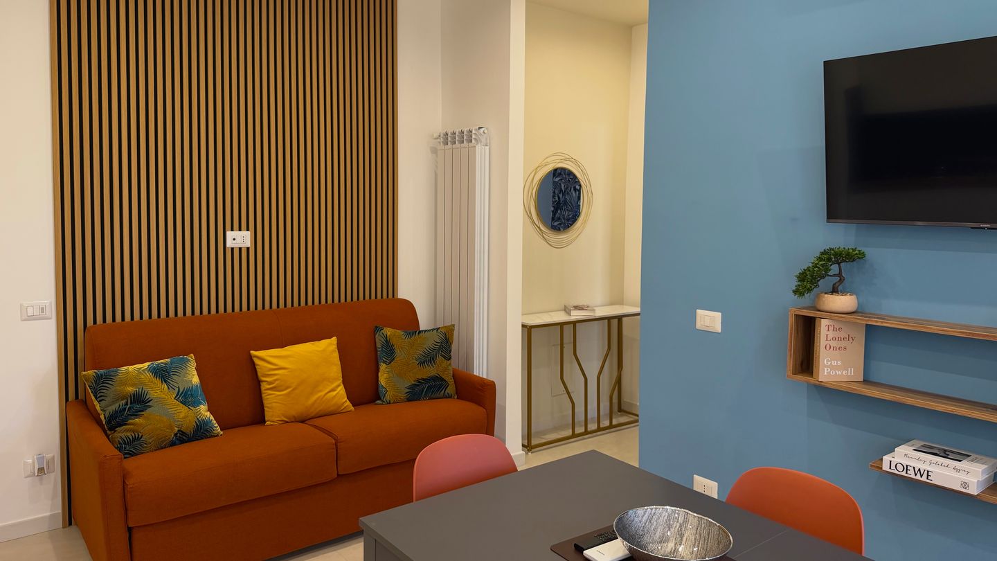 Orange sofa bed, dining table and light blue wall with the TV