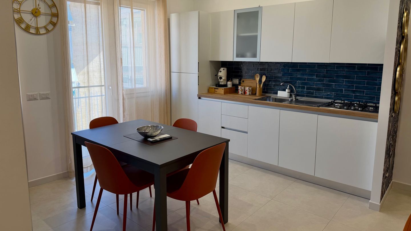 White kitchen with blue tiles and a dining table by the window