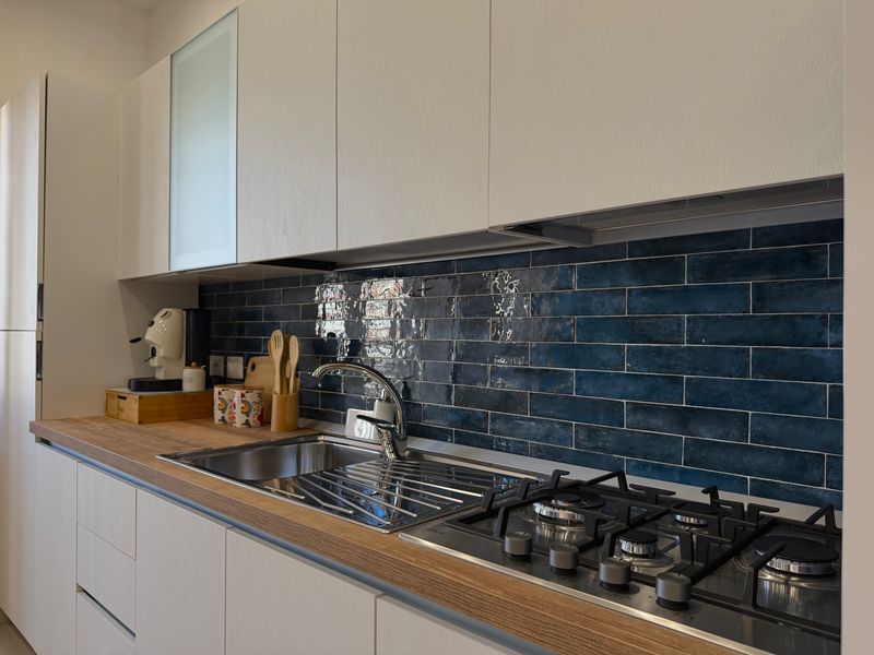 Hob and sink with the kitchen's glossy blue tiles